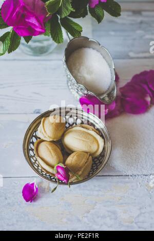 Leckere hausgemachte Cookies Nüsse, Weißzucker und wild rose Blumen auf weißem Hintergrund - Holz flach Essen Stockfoto