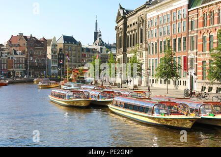 AMSTERDAM, NIEDERLANDE, 6. Juni 2018: Schöne Aussicht auf die Amstel mit vielen Touristen Schiffe und Universität Amsterdam auf dem Hintergrund Stockfoto