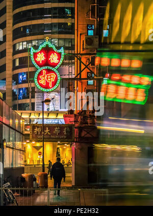 Hongkong - 09. Februar 2018 - Motion Blur of Moving Bus and Silhouette under Neon Lights at Night, Hongkong Stockfoto