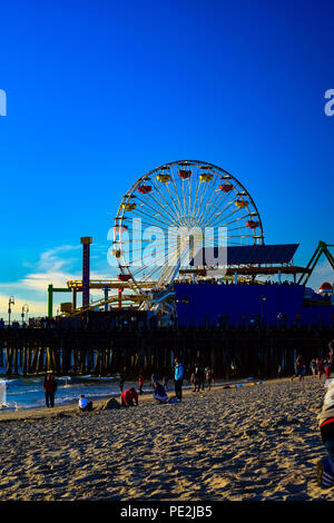 Die Menschen genießen die letzten Minuten vor Sonnenuntergang am Strand in Santa Monica, Kalifornien mit der Pier im Hintergrund Stockfoto