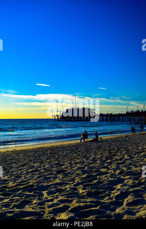 Die Menschen genießen die letzten Minuten vor Sonnenuntergang am Strand in Santa Monica, Kalifornien mit der Pier im Hintergrund Stockfoto