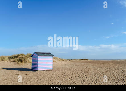 Eine einzelne Beach Hut allein stehend auf einem Sandstrand. Stockfoto