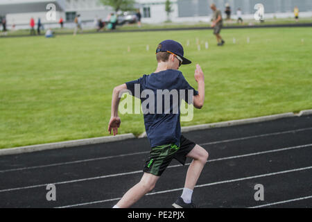 Junge in Track & Field der konkurrierenden, Langstreckenrennen, in kurzen Hosen, T-Shirt, Hut und Sonnenbrille. Model Released Stockfoto