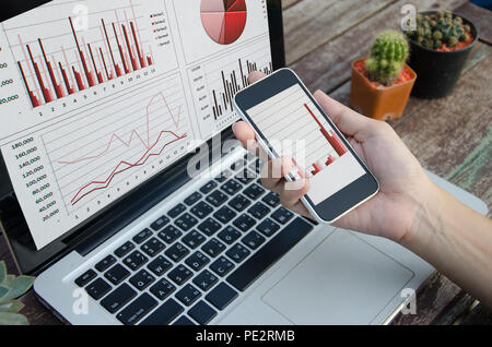 Nahaufnahme der Laptop mit Grafiken, Diagrammen und Tabellen auf dem Bildschirm am Tisch. Stockfoto