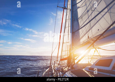 Segelboot im offenen Meer bei Sonnenuntergang, schöne luxuriöse Yacht Kreuzung Ozean Stockfoto