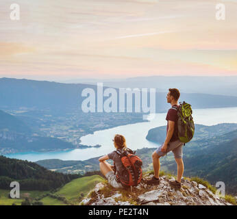 Paar Wanderer entspannen auf der Oberseite des Berges mit herrlichen Panoramablick im Freien, zwei Touristen Backpacker während der Wanderung, Abenteuer Flitterwochen Stockfoto