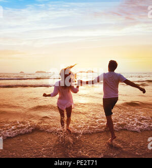 Glückliches Paar auf Hochzeitsreise urlaub reisen, romantischen Traum Strand Urlaub, Glück Hintergrund, Silhouetten von Mann und Frau, zum Meer bei Sun Stockfoto