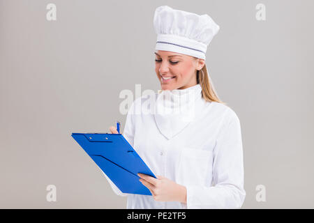 Schöne Köchin hält Kochbuch und ein neues Rezept. Stockfoto