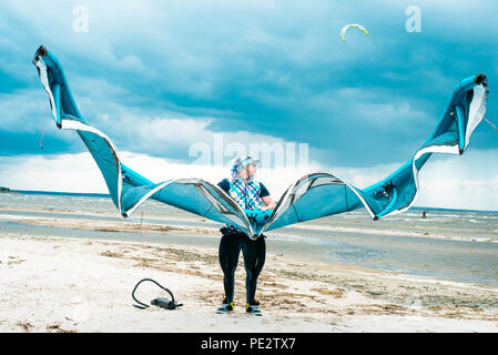 Kitesurfer hält seinen Drachen mit einem Sturm im Hintergrund in einem schönen Portrait bei stürmischem Wetter Stockfoto