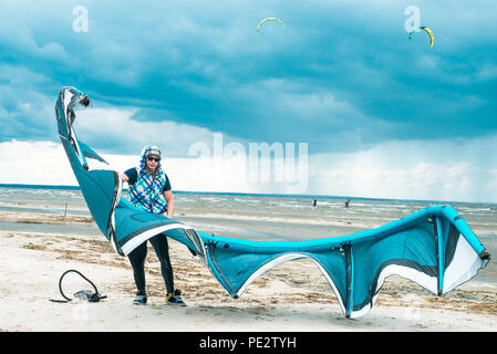 Kitesurfer hält seinen Drachen mit einem Sturm im Hintergrund in einem symmetrischen Portrait mit Kite Stockfoto