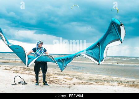 Kitesurfer hält seinen Drachen mit einem Sturm im Hintergrund in einem symmetrischen Portrait mit Kite Stockfoto