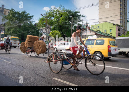 Geschäftige Straßen mit Autos und Fahrräder und Dreiräder in Yangon, Myanmar Stockfoto