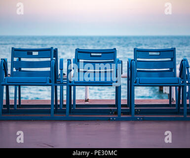 Mittelmeer und berühmte blaue Stühle auf der Promenade des Anglais bei Sonnenuntergang in Nizza, Cote d'Azur, Frankreich Stockfoto