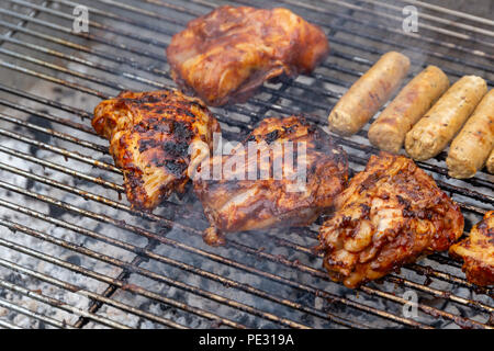 Mariniertes Huhn Stücke und vegetarische Würstchen auf dem Grill zubereitet Stockfoto