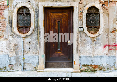 Fassade eines alten Hauses mit einer hölzernen Tür und verzierten Fenstern in Venedig, Italien Stockfoto