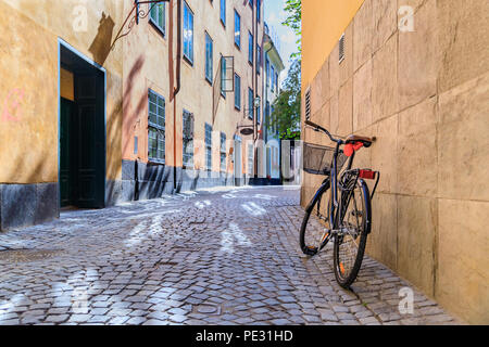 Schweden malerische Straße mit Kopfsteinpflaster im malerischen Gamla Stan, Stockholms älteste Nachbarschaft. Geparkt Fahrrad gegen ein Gebäude lehnend. Radfahren ist ein po Stockfoto