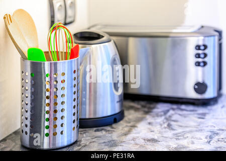 Bunte Küche Werkzeuge und Küchengeräte aus Edelstahl in einem modernen kitechen auf einer marmorarbeitsplatte Stockfoto