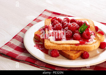 Toast mit Frischkäse und Himbeeren auf Textil Serviette Stockfoto