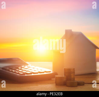Haus und Finanzen mit Taschenrechner mit Münzen auf Holz Tisch Stockfoto