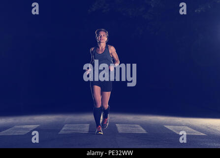 Fit muskulös Läuferin Training für Marathon läuft in der Nacht auf schöne Straße in der Natur. Stockfoto