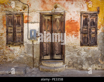 Die Front eines alten Chalki Haus mit abblätternde Farbe und alte hölzerne Tür und Fensterläden. Stockfoto