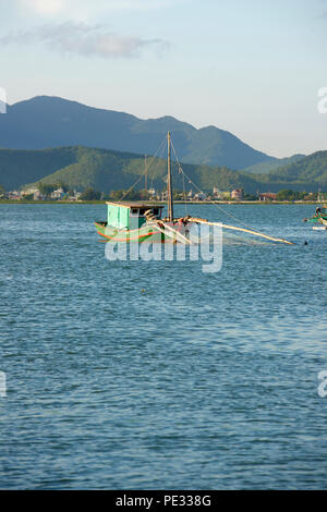 Eine kleine Fischerboote leuchten durch warmes Sonnenlicht in Bai Tu Long Bay, North Vietnam. Stockfoto