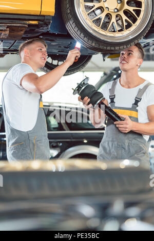 Zwei auto Mechanik Analyse der Felgen eines angehobenen Fahrzeug Stockfoto