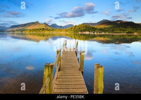 Eine alte Steg am Wasser des Derwent Water in Cumbria mit scheint die Sonne auf den Bergen in der Ferne. Stockfoto