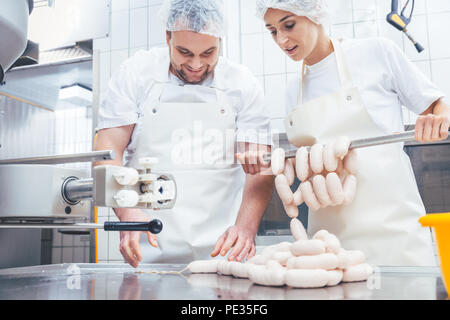 Team von Metzger Füllung Würstchen in der Fleisch verarbeitenden Industrie Stockfoto