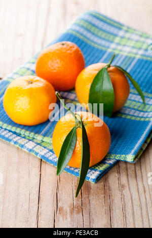 Mandarinen mit Blättern auf Holzuntergrund Stockfoto