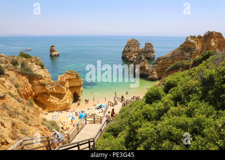 LAGOS, PORTUGAL - 23. JUNI 2018: die erstaunliche Landschaft mit Menschen klettern Holztreppe zu Praia Camilo Strand in der Nähe von Lagos, Algarve, Portugal Stockfoto