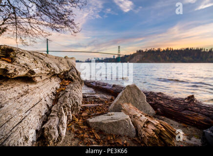 Melden Sie sich auf dem Strand mit der Lions Gate Bridge im Hintergrund bei Sonnenuntergang. Stockfoto