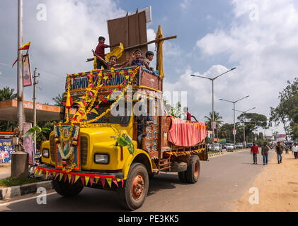 Mellahalli, Karnataka, Indien - November 1, 2013: Karnataka Rajyotsava Parade. Eine gelbe Dump Truck mit Kindern geladen schließt die Parade. Fahnen und Fl Stockfoto