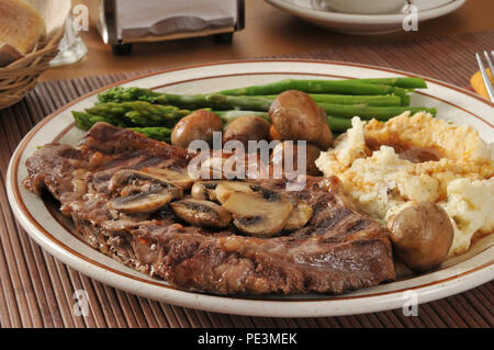 Ein Gegrilltes Rib Steak mit sautierten Pilzen, Spargel und Kartoffelpüree Stockfoto