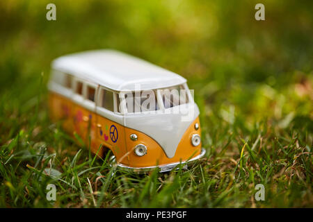 Orange VW Bus Spielzeug Figur mit Hippie Protokolle in der GEENEN Gras Stockfoto