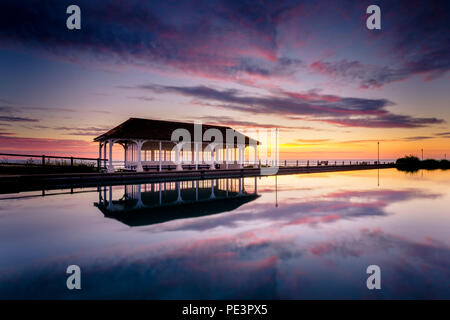 Ein feuerner Sonnenaufgang über dem Bootsee an der Promenade von Sheringham. Stockfoto