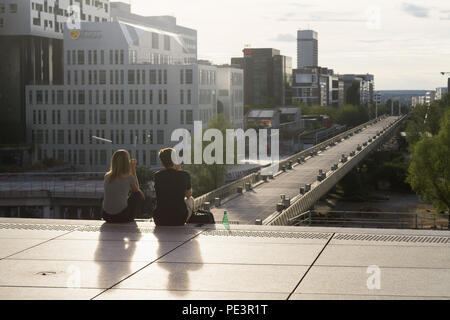 Paris La Defense - Paar sitzt auf der Treppe des Grand Arche in La Défense, mit Blick über die Fußgängerbrücke. Paris, Frankreich, Europa. Stockfoto