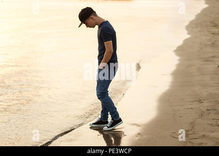 Jugendliche sehen das Wasser am Strand im Abendlicht Stockfoto