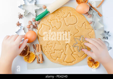 Kleines Mädchen Hand macht Lebkuchen Plätzchen aus dem Teig für Weihnachten auf weißer Tisch. Urlaub Konzept Stockfoto