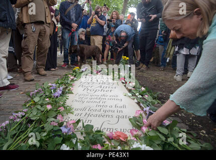 Eine Frau legt eine Blume von einem Grabstein für William Blake in Bunhill Fields in London, nachdem es enthüllt ist. Stockfoto