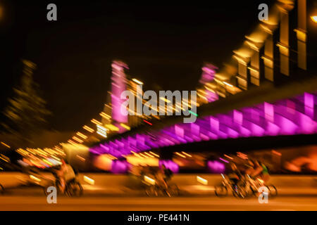 Motion verschwommenes Bild von Reiten Radfahrer Silhouetten auf einem hellen Hintergrund, Brücke, city night Illumination, Bewegungsunschärfe. Konzept des modernen gesunden Lebensstil Stockfoto