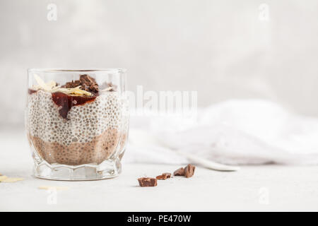 Chia Pudding mit Schokolade, Mandeln und Berry Konfitüre, weißen Hintergrund. Raw vegan Dessert. Saubere Konzept essen. Stockfoto