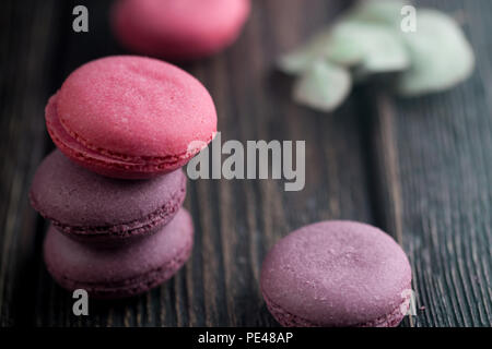 Gruppe der Macarons aus Erdbeeren, Sahne, Schokolade und Heidelbeeren. Rustikale Foto. Getönt. Stockfoto