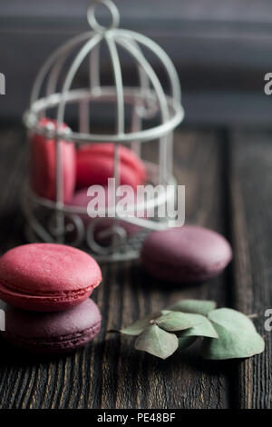 Gruppe der Macarons aus Erdbeeren, Sahne, Schokolade und Heidelbeeren. Rustikale Foto. Getönt. Stockfoto