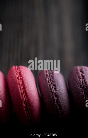 Gruppe der Macarons aus Erdbeeren, Sahne, Schokolade und Heidelbeeren. Rustikale Foto. Getönt. Stockfoto