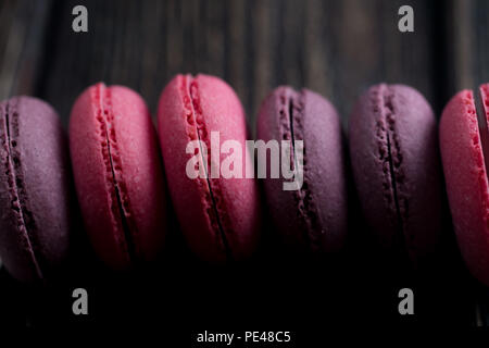 Gruppe der Macarons aus Erdbeeren, Sahne, Schokolade und Heidelbeeren. Rustikale Foto. Getönt. Stockfoto