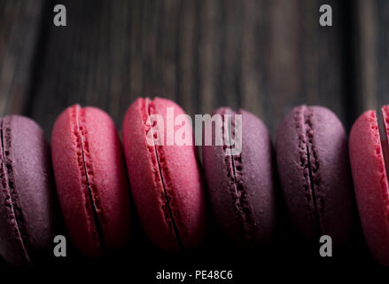 Gruppe der Macarons aus Erdbeeren, Sahne, Schokolade und Heidelbeeren. Rustikale Foto. Getönt. Stockfoto