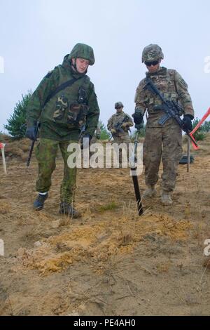 Litauische Landstreitkräfte Cpl. Nerijus Zvalionis, Links, ein Eingeborener von Kedainiai und explosiven Verpackungsverordnung Entsorgung Experte in die juozas Vitkus Ingenieur Bataillon zugeordnet, Führer der U.S. Army Fallschirmjäger SPC. Brendon Carney, ein Eingeborener von Guilford, Anschl. zu Hund Unternehmen, 1.BATAILLON, 503Rd Infanterie Regiment, 173Rd Airborne Brigade zugeordnet, die in der Anwendung eines Minesweeper, genannt "Gifts" nicht detonierten Kampfmitteln während der Übung Ingenieur Thunder 2015 gehalten am Großen Litauischen Hetman Jonusas Radvila Training Regiment, in Rukla, Litauen, Sept. 9, 2015 begraben zu erkennen. Ingenieur Donner wird bot verbessern Stockfoto