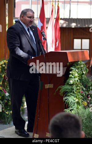 KABUL, Afghanistan (Sept. 9, 2015) Mel Booker, DynCorp International Program Manager der ANA/ANP Berater und Mentor Programme, spricht mit den Koalitionstruppen während ein Denkmal für Kollegen, die von einem Angriff auf ihren Konvoi 12.08.22 in Kabul gestorben gedenken. Richard McEvoy, Corey Dodge und Barry Sutton wurden zivile Auftragnehmer von DynCorp, die auf den Schutz für das Beraterteam der afghanischen nationalen Armee und der afghanischen nationalen Polizei im Rahmen der NATO-geführten Mission diente der entschlossenen Unterstützung. Die Destille Garten wurde mit diesen ihren Respekt an die gefallenen Freunde einschließlich s verpackt Stockfoto