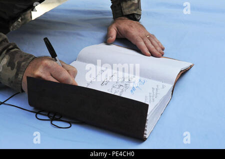 KABUL, Afghanistan (Sept. 9, 2015) ein service Mitglied meldet ein Gedenkbuch für Corey Dodge nach einer Zeremonie zu Ehren sein Opfer zum Schutz detail für das Beraterteam der afghanischen nationalen Armee und der afghanischen nationalen Polizei im Rahmen der NATO-geführten Mission der entschlossenen Unterstützung. Dodge, Richard McEvoy und Barry Sutton, zivile Auftragnehmer von DynCorp International, starb bei einem Angriff auf ihren Konvoi 12.08.22 in Kabul. Die trauerfeier an der Destille Garten gehalten wurde mit diesen zahlen ihren Respekt einschließlich Führungskräfte von der entschlossenen Unterstützung der US-Botschaft - Kabul, DynCorp Inte Stockfoto